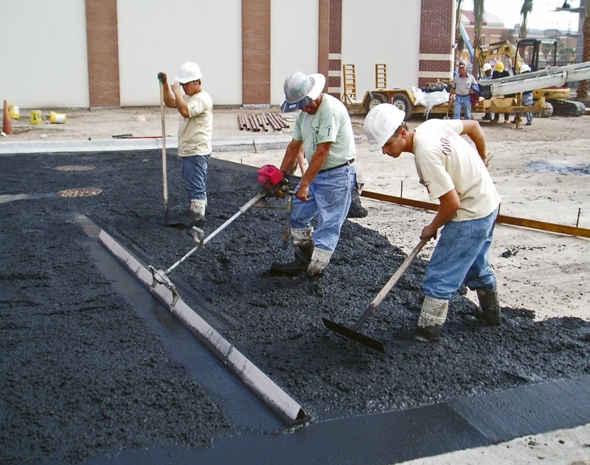 Leveling concrete while installing a new black driveway at a Tampa retail store in a Shopping Center using a vibrating screed.
