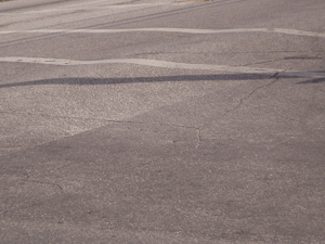 This road shows rutting beginning as asphalt softens under the hot sun and heavy vehicles. Ruts deepen, cracks form, and then resurfacing is needed.